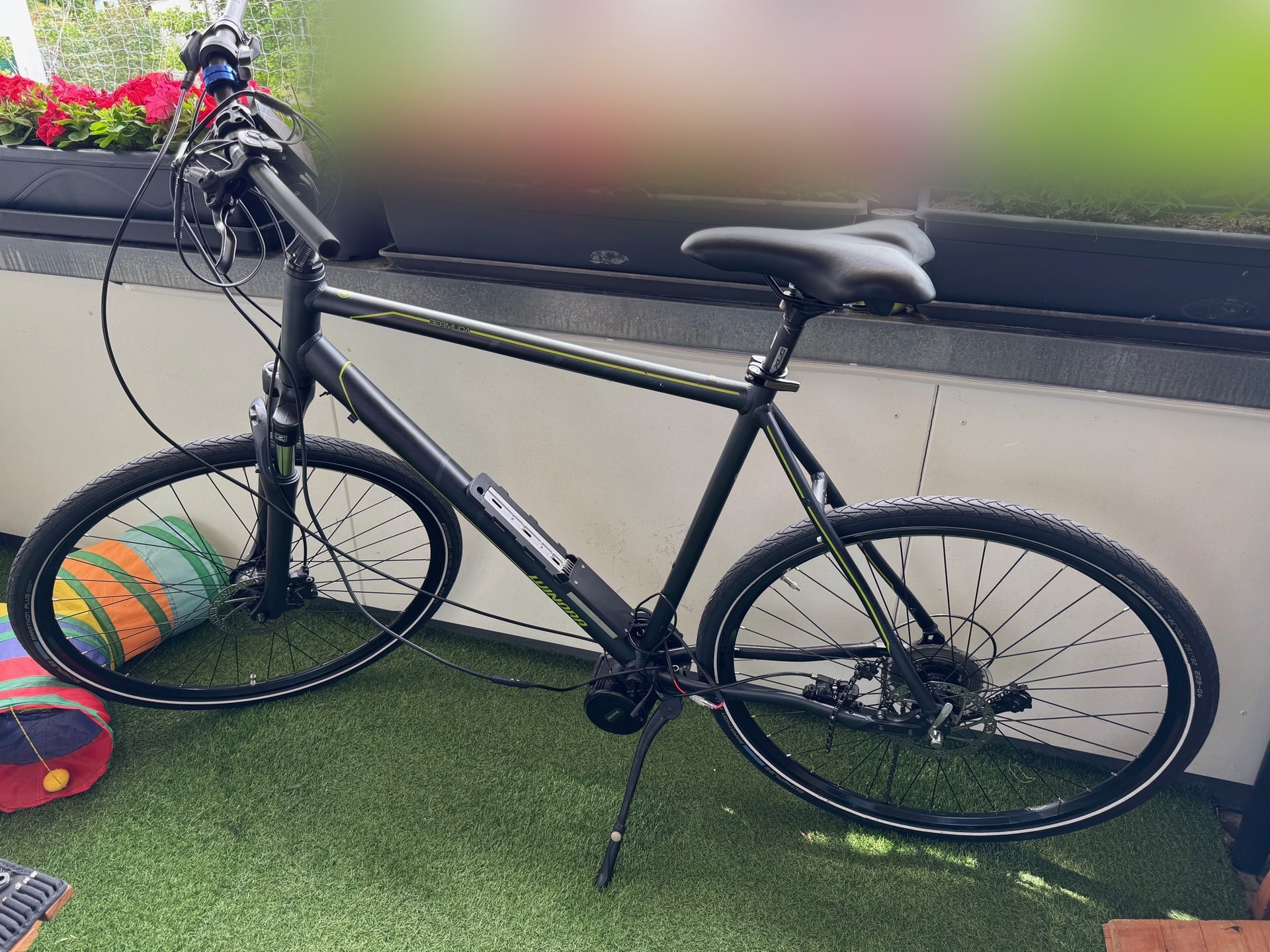 The bike on a balcony with the Bafang motor fitted at the bottom bracket and the battery on the downtube, wiring hanging loose at the front